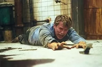 "Saw" (2004) filminden bir sahne: İki adam, terk edilmiş ve karanlık bir banyoda zincirlenmiş halde hayatta kalma mücadelesi verirken, aralarındaki ceset ve kaset oynatıcı ile korku dolu bir bulmacayı çözmeye çalışıyor